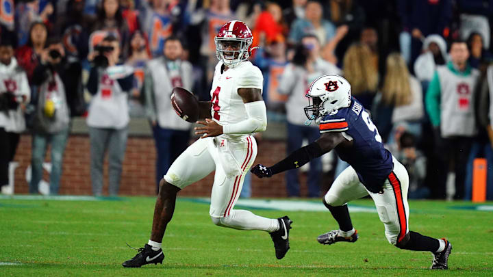 Nov 25, 2023; Auburn, Alabama, USA; Alabama Crimson Tide quarterback Jalen Milroe (4) scrambles up the field against Auburn Tigers linebacker Eugene Asante (9) during the third quarter at Jordan-Hare Stadium. Mandatory Credit: John David Mercer-Imagn Images