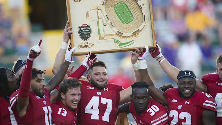 Sep 3, 2016; Green Bay, WI, USA;   Wisconsin Badgers players holds up the Lambeau Field College Classic trophy following the game against the LSU Tigers at Lambeau Field. Mandatory Credit: Jeff Hanisch-Imagn Images
