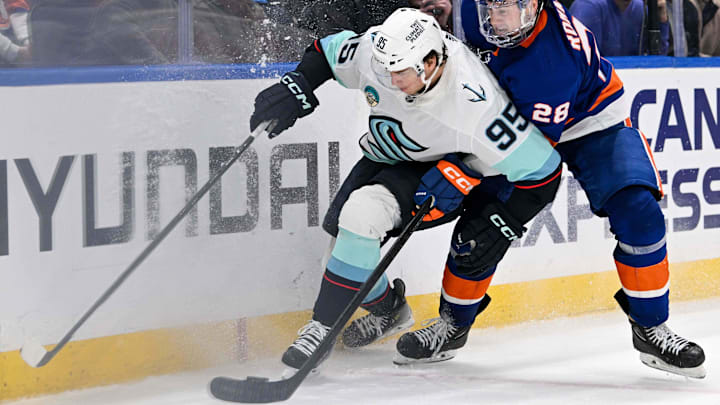 Feb 13, 2024; Elmont, New York, USA; New York Islanders defenseman Alexander Romanov (28) and Seattle Kraken left wing Andre Burakovsky (95) battle for the puck along the boards during the third period at UBS Arena. Mandatory Credit: Dennis Schneidler-Imagn Images