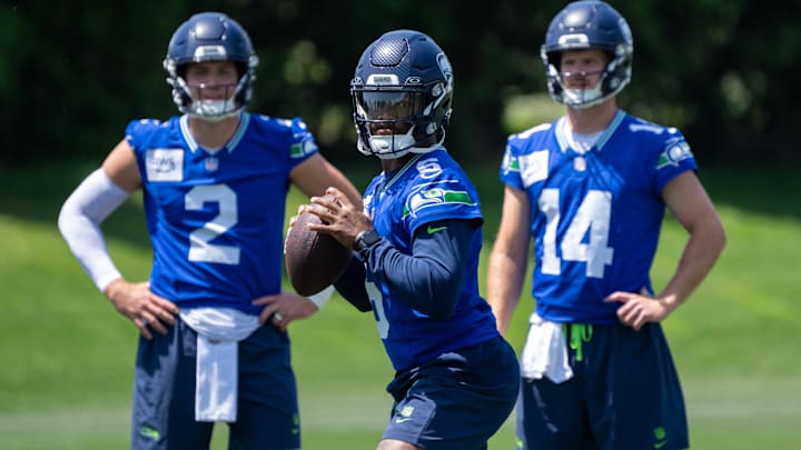 Seattle Seahawks QB Jalen Milroe looks to pass as Drew Lock and Sam Darnold watch at mini-camp.