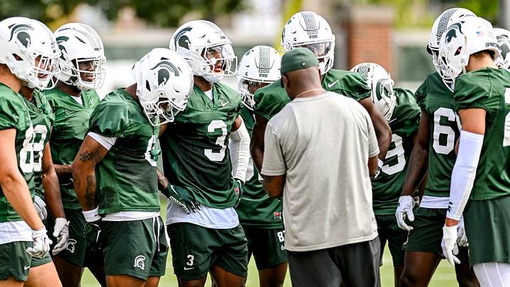 Michigan State's wide receivers gather around coach Courtney Hawkins during the first day of football camp on Tuesday, July 30, 2024, in East Lansing.