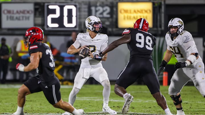 Aug 28, 2025; Orlando, Florida, USA; UCF Knights quarterback Tayven Jackson (2) rolls back to pass as Jacksonville State Gamecocks defensive end Emmanuel Oyebadejo (99) moves in during the second quarter at Acrisure Bounce House. Mandatory Credit: Mike Watters-Imagn Images