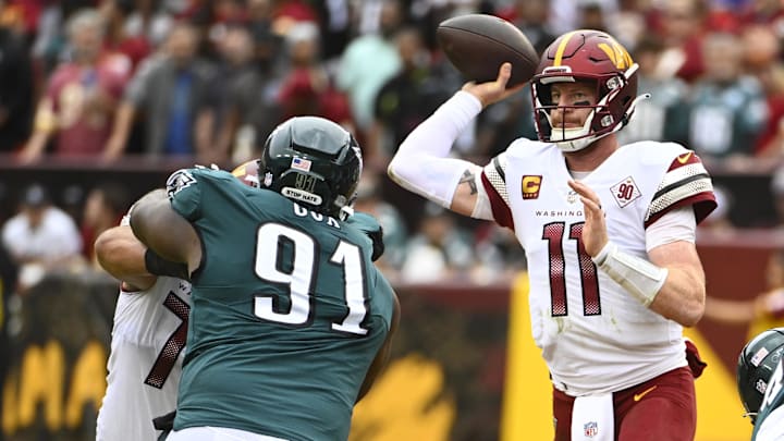 Sep 25, 2022; Landover, Maryland, USA; Washington Commanders quarterback Carson Wentz (11) passes as Philadelphia Eagles defensive tackle Fletcher Cox (91) defends during the second half at FedExField. Mandatory Credit: Brad Mills-Imagn Images