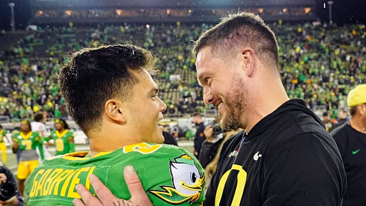 Oregon quarterback Dillon Gabriel, left, and coach Dan Lanning embrace after defeating Maryland at Autzen Stadium.