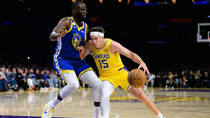 Oct 21, 2025; Los Angeles, California, USA; Los Angeles Lakers guard Austin Reaves (15) drives against Golden State Warriors forward Draymond Green (23) during the first half at Crypto.com Arena. Mandatory Credit: William Liang-Imagn Images