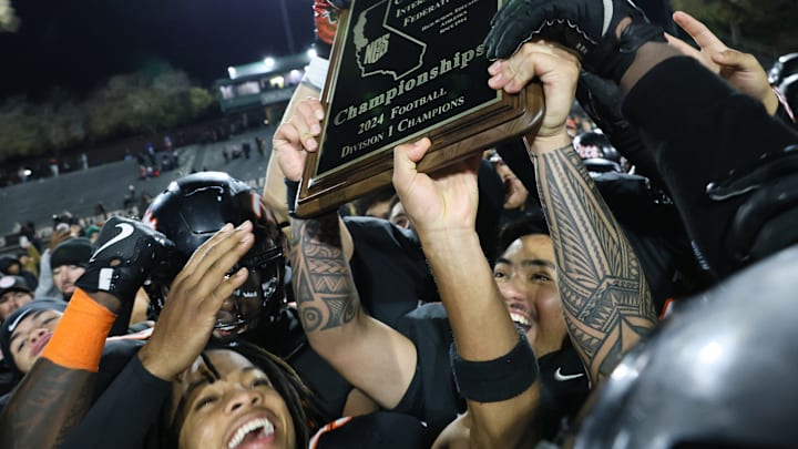 Members of the Pittsburg Pirates hold up the North Coast Section Division 1 hardware after a 35-28 win over San Ramon Valley Friday at Diablo Valley College. It was Pittsburg's fourth straight Division 1 title. The Pirates will now likely meet Folsom in the CIF State Division 1-AA Northern Region title game. 