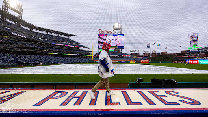 Apr 3, 2024; Philadelphia, Pennsylvania, USA; A Philadelphia Phillies staff member walks on top of the dugout during a rain delay before a game against the Cincinnati Reds at Citizens Bank Park.