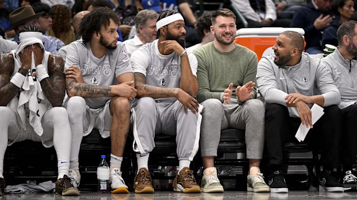 Nov 27, 2024; Dallas, Texas, USA; (from left) Dallas Mavericks center Dereck Lively II and forward Markieff Morris and guard Luka Doncic sit on the team bench during the second quarter of the game between the Mavericks and the New York Knicks at the American Airlines Center. Mandatory Credit: Jerome Miron-Imagn Images