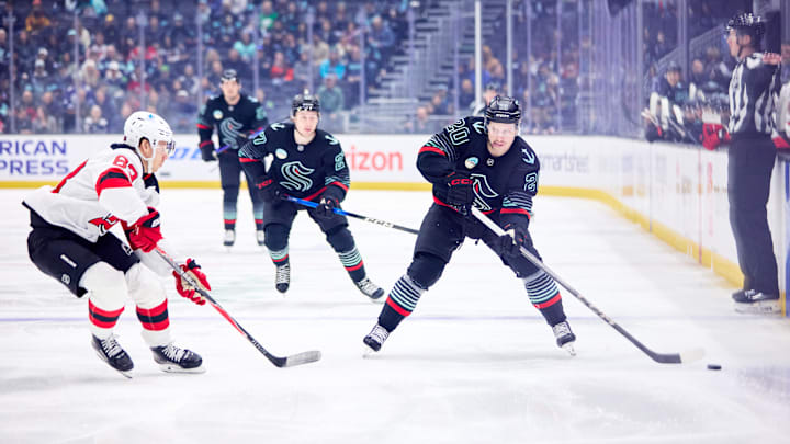 Jan 25, 2026; Seattle, Washington, USA; Seattle Kraken right wing Eeli Tolvanen (20) looks to pass as New Jersey Devils center Juho Lammikko (83) defends during the first period at Climate Pledge Arena. Mandatory Credit: Blake Dahlin-Imagn Images