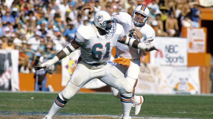 Guard Roy Foster (61) protects quarterback Dan Marino during the 1985 AFC Divisional Playoff Game against the Cleveland Browns at the Orange Bowl. Guard Roy Foster (61) protects quarterback Dan Marino during the 1985 AFC Divisional Playoff Game against the Cleveland Browns at the Orange Bowl.