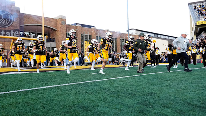 Sep 13, 2025; Laramie, Wyoming, USA; Wyoming Cowboys head coach Jay Sawvel (right) leads the team out before the game against the Utah Utes at Jonah Field at War Memorial Stadium. Mandatory Credit: Ron Chenoy-Imagn Images