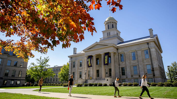People walk past a tree changing colors near the Old Capitol building on the University of Iowa campus Thursday, Oct. 17, 2024 in Iowa City, Iowa.