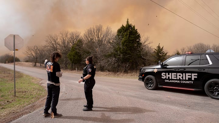 A resident talks with an Oklahoma County Sheriff's deputy near during a wildfire Triple X Road and Coffee Creek in Luther, Okla., Friday, March 14, 2025.