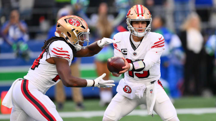 Oct 10, 2024; Seattle, Washington, USA; San Francisco 49ers quarterback Brock Purdy (13) hands the ball off to running back Jordan Mason (24) during the first half against the Seattle Seahawks at Lumen Field. Mandatory Credit: Steven Bisig-Imagn Images