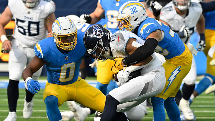 Nov 10, 2024; Inglewood, California, USA; Los Angeles Chargers linebacker Daiyan Henley (0) and safety Alohi Gilman (32) tackle Tennessee Titans wide receiver Nick Westbrook-Ikhine (15) during the second quarter at SoFi Stadium. Mandatory Credit: Robert Hanashiro-Imagn Images
