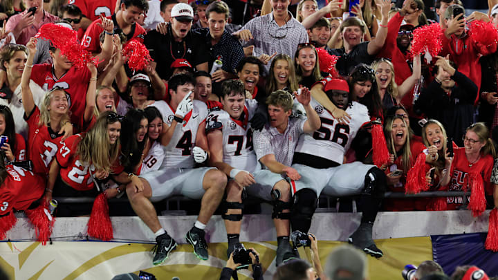 From left, Georgia Bulldogs defensive back KJ Bolden (4), offensive lineman Drew Bobo (74) and offensive lineman Micah Morris (56) leap into the student section after an NCAA football game, Saturday, Nov. 1, 2025, at EverBank Stadium in Jacksonville, Fla. Georgia held off Florida 24-20. [Corey Perrine/Florida Times-Union]