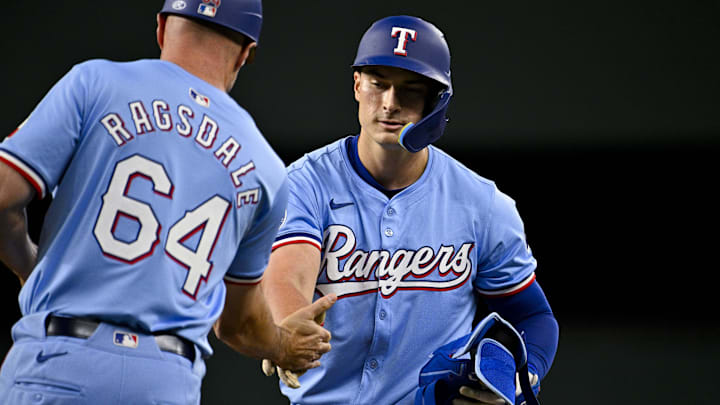 Texas Rangers first base coach Corey Ragsdale (64) congratulates Rangers pinch hitter Justin Foscue (56) after Ragsdale gets his first career MLB hit and run batted in during the ninth inning against the Houston Astros at Globe Life Field. Texas Rangers first base coach Corey Ragsdale (64) congratulates Rangers pinch hitter Justin Foscue (56) after Ragsdale gets his first career MLB hit and run batted in during the ninth inning against the Houston Astros at Globe Life Field.