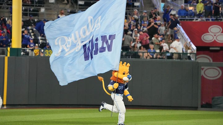 Sep 6, 2024; Kansas City, Missouri, USA; The Kansas City Royals mascot Sluggerrr runs on field with a large flag after the win over the Minnesota Twins at Kauffman Stadium. Mandatory Credit: Denny Medley-Imagn Images