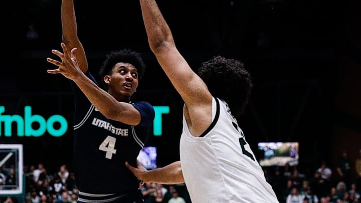Mar 1, 2025; Fort Collins, Colorado, USA; Utah State Aggies guard Ian Martinez (4) passes the ball under pressure from Colorado State Rams forward Rashaan Mbemba (21) in the second half at Moby Arena. Mandatory Credit: Isaiah J. Downing-Imagn Images