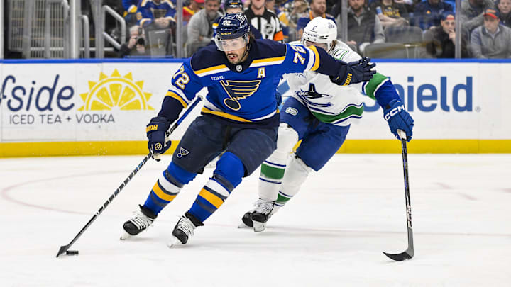 Mar 20, 2025; St. Louis, Missouri, USA;  St. Louis Blues defenseman Justin Faulk (72) controls the puck as Vancouver Canucks right wing Brock Boeser (6) defends during the first period at Enterprise Center. Mandatory Credit: Jeff Curry-Imagn Images