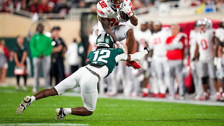Sep 28, 2024; East Lansing, Michigan, USA; Ohio State Buckeyes running back TreVeyon Henderson (32) hurdles over Michigan State Spartans defensive back Justin Denson Jr. (12) in the second half at Spartan Stadium on Saturday.