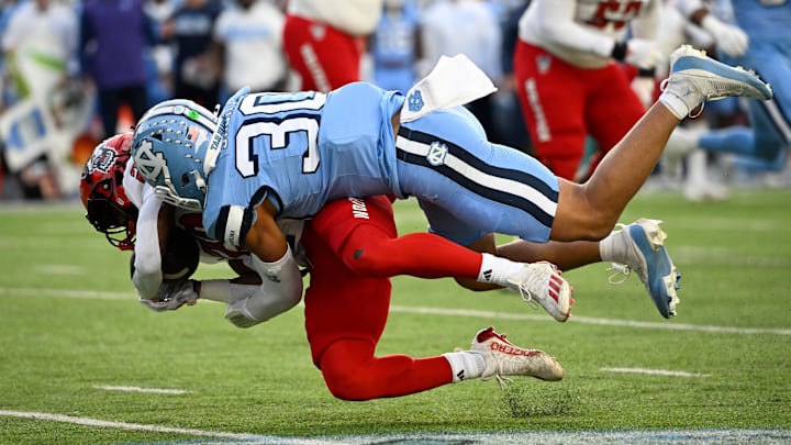 Nov 30, 2024; Chapel Hill, North Carolina, USA; North Carolina State Wolfpack running back Hollywood Smothers (20) is tacked by North Carolina Tar Heels linebacker Michael Short (30) in the first quarter at Kenan Memorial Stadium. Mandatory Credit: Bob Donnan-Imagn Images