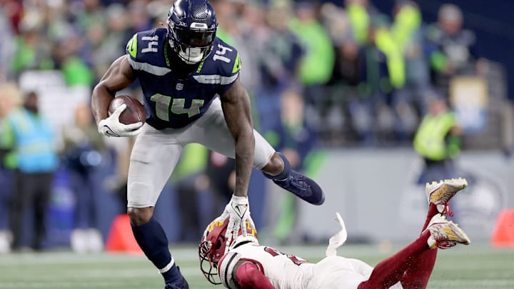 SEATTLE, WASHINGTON - NOVEMBER 12: DK Metcalf #14 of the Seattle Seahawks avoids a tackle by Jartavius Martin #20 of the Washington Commanders during the fourth quarter at Lumen Field on November 12, 2023 in Seattle, Washington.
