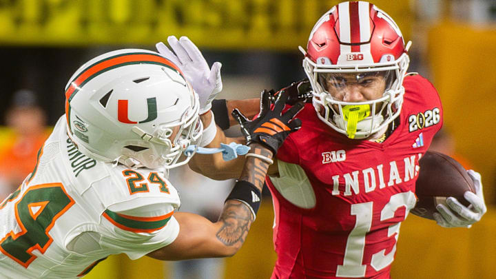 Indiana's Elijah Sarratt (13) stiff arms Miami's Ethan O'Connor (24) during the College Football Playoff National Championship college football game at Hard Rock Stadium in Miami Gardens on Monday, Jan. 19, 2026. Indiana's Elijah Sarratt (13) stiff arms Miami's Ethan O'Connor (24) during the College Football Playoff National Championship college football game at Hard Rock Stadium in Miami Gardens on Monday, Jan. 19, 2026.