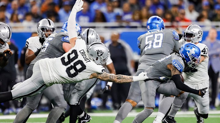 Detroit Lions running back Jahmyr Gibbs (26) is tackled by Las Vegas Raiders defensive end Maxx Crosby (98) 
