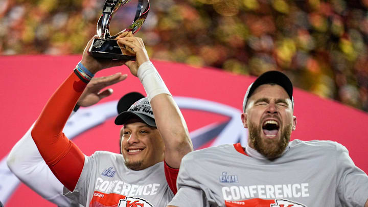 Patrick Mahomes raises the Lamar Hunt Trophy while Travis Kelce celebrates.