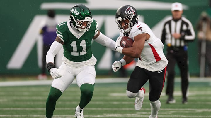 Nov 30, 2025; East Rutherford, New Jersey, USA; Atlanta Falcons running back Bijan Robinson (7) rushes the ball past New York Jets linebacker Jermaine Johnson (11)  during the first half at MetLife Stadium. Mandatory Credit: Vincent Carchietta-Imagn Images