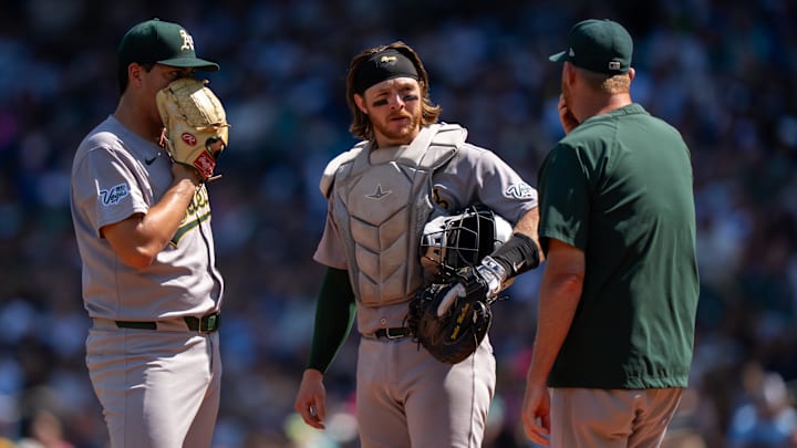 Aug 24, 2025; Seattle, Washington, USA; Athletics Athletics starting pitcher Jacob Lopez (57), left, catcher Willie MacIver (65), center, and pitching coach Scott Emerson meet at the mound during the second inning against the Seattle Mariners at T-Mobile Park. Mandatory Credit: Stephen Brashear-Imagn Images