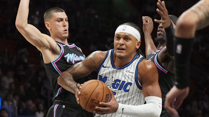 Mar 14, 2026; Miami, Florida, USA;  Orlando Magic forward Paolo Banchero (5) splits the defense of Miami Heat guard Tyler Herro (14) and Miami Heat center Bam Adebayo (13) during the first half at Kaseya Center. Mandatory Credit: Jim Rassol-Imagn Images