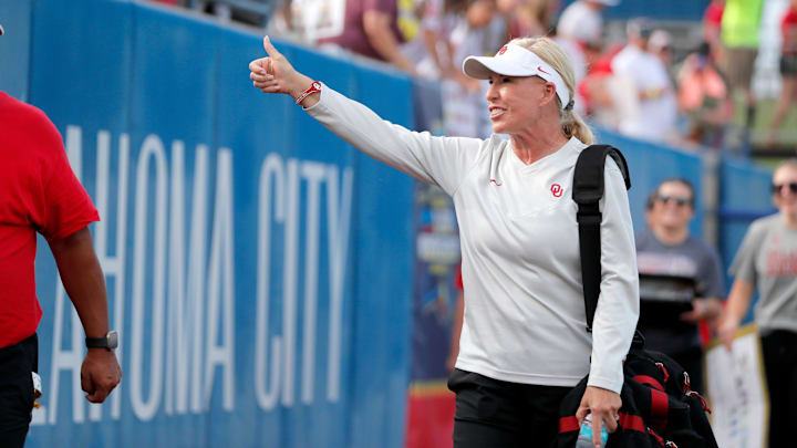 Oklahoma coach Patty Gasso gestures to fans as she walks on the field before Game 2 of the NCAA softball Women's College World Series Championship Series game between the Oklahoma Sooners (OU) and Texas Longhorns at Devon Park in Oklahoma City.