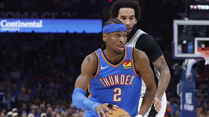 Oklahoma City Thunder guard Shai Gilgeous-Alexander (2) moves the ball around San Antonio Spurs forward Julian Champagnie (30)