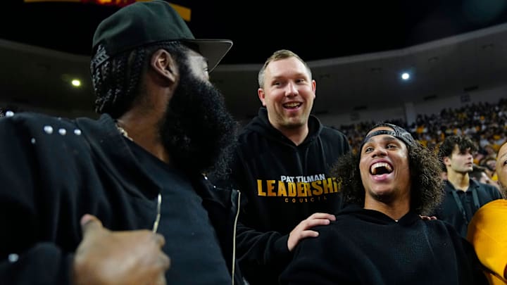 Arizona State football coach Kenny Dillingham (center) talks with former Arizona State guard James Harden (L) and wide receiver Jordyn Tyson during a game at Desert Financial Arena in Tempe, Ariz. on Jan. 31, 2026.