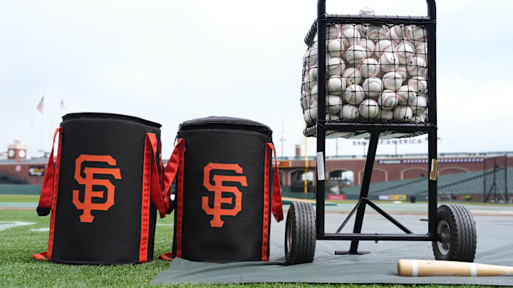 Ball bags with the San Francisco Giants logo sit on the field.
