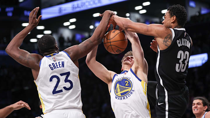 Feb 5, 2024; Brooklyn, New York, USA; Golden State Warriors guard Brandin Podziemski (2) and forward Draymond Green (23) rebound against Brooklyn Nets center Nic Claxton (33) during the second half at Barclays Center. Mandatory Credit: Vincent Carchietta-Imagn Images