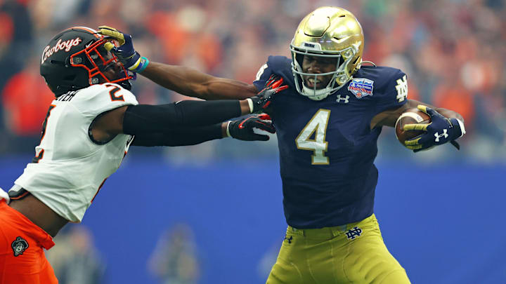 Jan 1, 2022; Glendale, Arizona, USA; Notre Dame Fighting Irish wide receiver Kevin Austin Jr. (4) stiff arms Oklahoma State Cowboys safety Tanner McCalister (2) in the first half during the 2022 Fiesta Bowl at State Farm Stadium. 