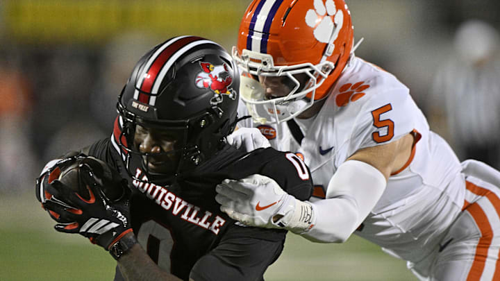 Nov 14, 2025; Louisville, Kentucky, USA;  Louisville Cardinals wide receiver Chris Bell (0) runs the ball against Clemson Tigers safety Ronan Hanafin (5) during the first half at L&N Federal Credit Union Stadium. Mandatory Credit: Jamie Rhodes-Imagn Images