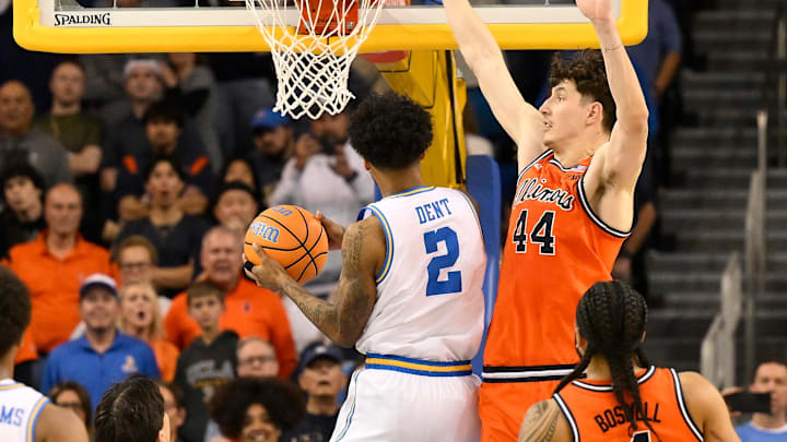 Feb 21, 2026; Los Angeles, California, USA; UCLA guard Donovan Dent (2) hangs in the air and scores the winning basket over Illinois center Zvonimir Ivisic (44) in overtime  at Pauley Pavilion presented by Wescom Financial. Mandatory Credit: Robert Hanashiro-Imagn Images