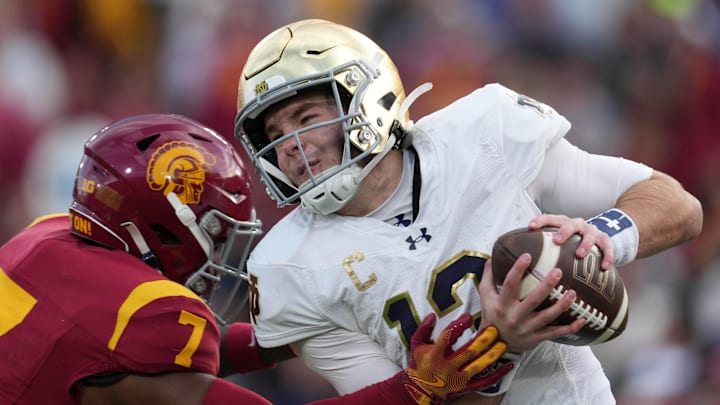 Nov 30, 2024; Los Angeles, California, USA; Notre Dame Fighting Irish quarterback Riley Leonard (13) is pressured by Southern California Trojans safety Kamari Ramsey (7) in the second half at United Airlines Field at Los Angeles Memorial Coliseum. Mandatory Credit: Kirby Lee-Imagn Images
