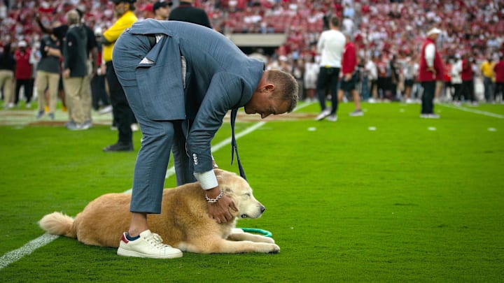 ESPN’s Kirk Herbstreit pets his dog Ben on the field before a game between the Georgia Bulldogs and Alabama Crimson Tide.