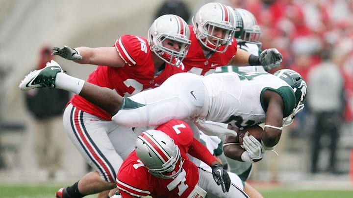 Ohio State Buckeyes Travis Howard (7) Storm Klein (32) and Andrew Sweat (42) team up to stop Michigan State Spartans running back Le'Veon Bell (24) in the first quarter of their NCAA football game at Ohio Stadium, October 1, 2011.