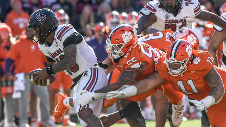 Nov 30, 2024; Clemson, South Carolina, USA; South Carolina quarterback LaNorris Sellers (16) runs by Clemson defensive tackle Payton Page (55) and defensive lineman Peter Woods (11) during the fourth quarter at Memorial Stadium. Mandatory Credit: Ken Ruinard-Imagn Images