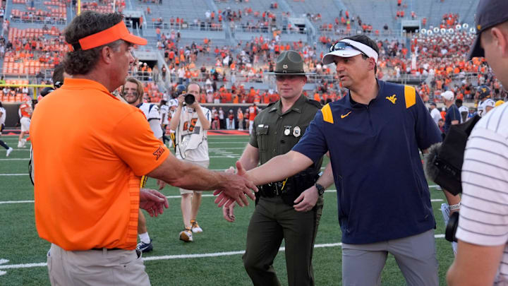 Oklahoma State coach Mike Gundy, left, shakes hands with West Virginia coach Neal Brown after a college football game between the Oklahoma State Cowboys (OSU) and the West Virginia Mountaineers at Boone Pickens Stadium in Stillwater, Okla., Saturday, Oct. 5, 2024.