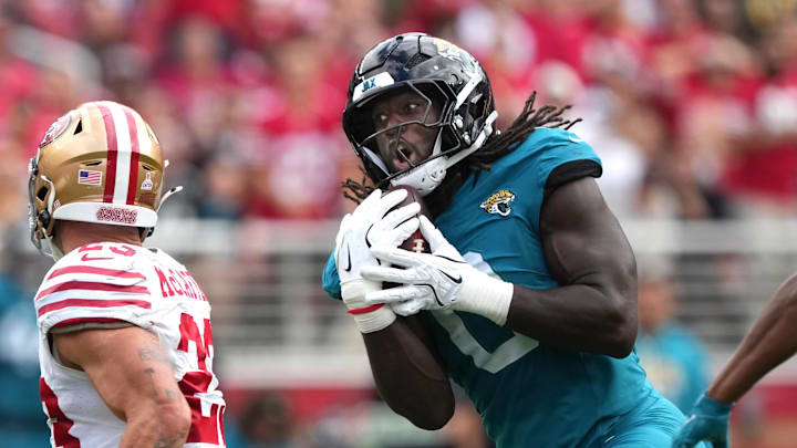 Sep 28, 2025; Santa Clara, California, USA; Jacksonville Jaguars linebacker Devin Lloyd (center) catches a bobbled ball by San Francisco 49ers running back Christian McCaffrey (left) for an interception during the second quarter at Levi's Stadium. Mandatory Credit: Darren Yamashita-Imagn Images