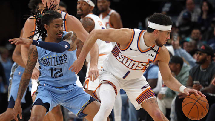 Feb 25, 2025; Memphis, Tennessee, USA; Phoenix Suns guard Devin Booker (1) dribbles as Memphis Grizzlies guard Ja Morant (12) defends during the first quarter at FedExForum. Mandatory Credit: Petre Thomas-Imagn Images