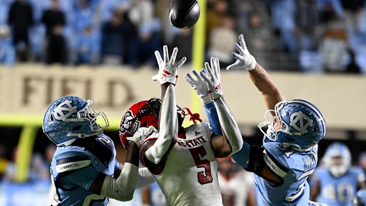 Nov 30, 2024; Chapel Hill, North Carolina, USA; North Carolina State Wolfpack wide receiver Noah Rogers (5) catches a 44 yard pass as North Carolina Tar Heels defensive backs Marcus Allen (29) and Will Hardy (31) defend in the fourth quarter at Kenan Memorial Stadium. Mandatory Credit: Bob Donnan-Imagn Images Nov 30, 2024; Chapel Hill, North Carolina, USA; North Carolina State Wolfpack wide receiver Noah Rogers (5) catches a 44 yard pass as North Carolina Tar Heels defensive backs Marcus Allen (29) and Will Hardy (31) defend in the fourth quarter at Kenan Memorial Stadium. Mandatory Credit: Bob Donnan-Imagn Images