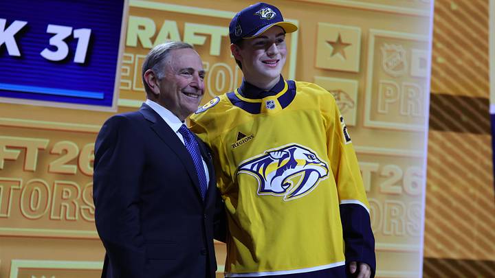 Jun 26, 2026; Buffalo, New York, USA; Tommy Bleyl reacts beside NHL commissioner Gary Bettman after being selected with the thirty first pick in the first round of the 2026 NHL Draft by the Nashville Predators at KeyBank Center. Mandatory Credit: Timothy T. Ludwig-Imagn Images